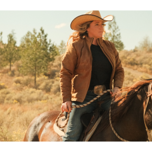 cowgirl riding a horse wearinng oilskin jacket